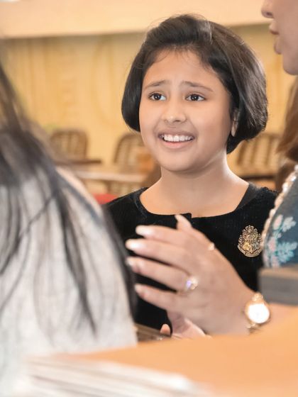 A candid shot capturing a young girl's animated expression as she talks with guests at her party.