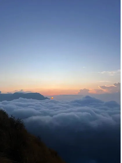 The sun peeking over the horizon, its first rays hitting the top of the cloud bed.
