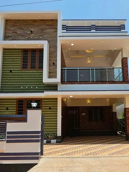 We use color and texture to create unique home exteriors, as seen in this design with green grooved panels and natural stone cladding. The large covered balcony on the first floor provides a comfortable and sheltered outdoor living area.