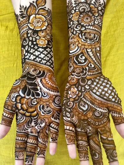 A top-down view of a rich Indo-Arabic design. The use of negative space on one hand contrasts beautifully with the dense floral work on the other, creating a unique and balanced look.