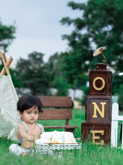 A thoughtful moment before the cake smash begins at this outdoor first birthday shoot.