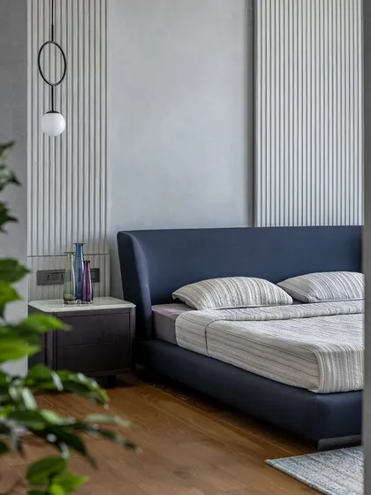 A view of the minimalist master bedroom, framed by a plant in the foreground, emphasizing the room's connection to natural elements.