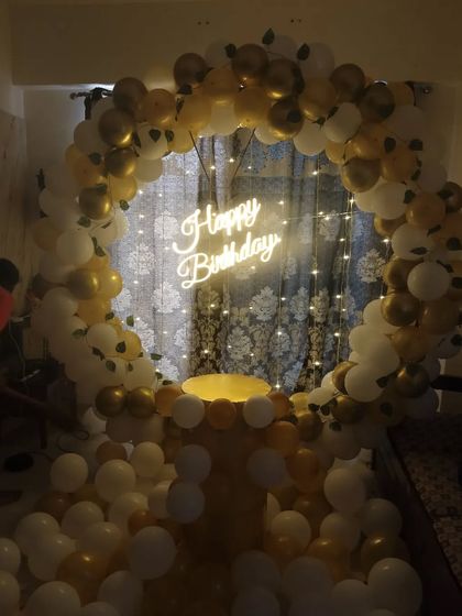 A classic gold and white balloon ring with a neon sign, perfect for an elegant birthday party at home.