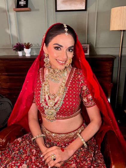 The joy of a bride who feels her absolute best. This radiant smile is the final touch to a perfect traditional red lehenga look.