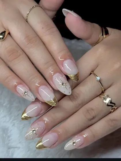 An elegant take on the French manicure, featuring almond-shaped extensions with a metallic gold tip. Each nail is accented with a delicate starburst rhinestone for a touch of luxury.