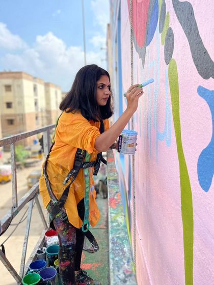 The artist at work on a large-scale exterior mural, showcasing the dedication and physical effort required to bring these monumental pieces to life. Every brushstroke is a choice, a sacrifice to the art.