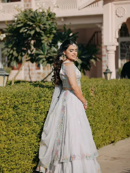 A graceful portrait of the bride in a light blue lehenga, posing in the gardens of a Rajasthani palace.