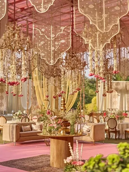 A beautiful lounge area under a canopy of blush drapes and floral chandeliers, with a central table creating a focal point for guests to gather and celebrate.