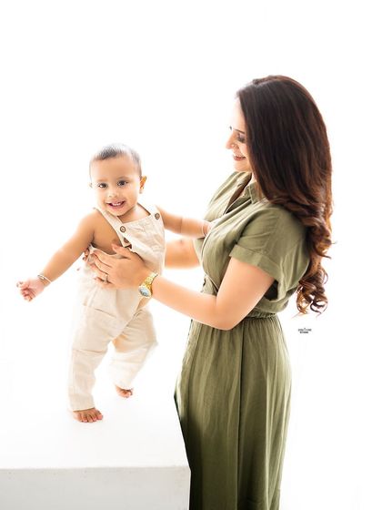 A mother helping her little one take his first steps. A precious milestone moment.
