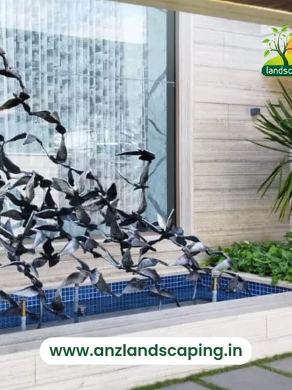 This custom water feature includes a dynamic metal sculpture of a flock of birds taking flight, creating a striking centerpiece for a modern villa landscape.