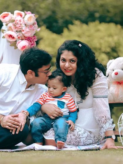 A sweet family picnic portrait. The parents share a loving moment with their baby, surrounded by props that create a charming and relaxed atmosphere.