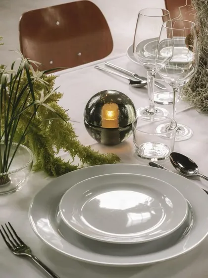 The Bocci 14p in Smoked Grey, used as a centerpiece on a beautifully set dining table. It provides an intimate, candle-like light without the worry of an open flame.