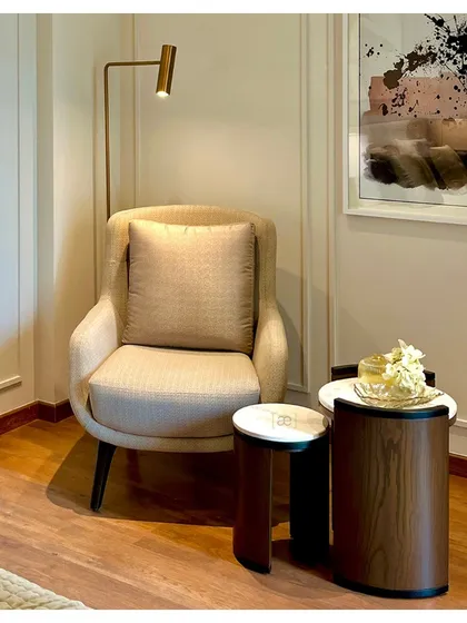 A detail shot of the reading nook, highlighting the elegant combination of textures and materials, from the upholstered chair to the marble and wood side tables.