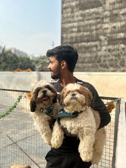 One of our team members holding two adorable Shih Tzus, soaking up the sun and the love.