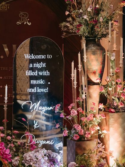 A personalized welcome sign on a mirror, surrounded by flowers and candles. This elegant detail at the sangeet entrance immediately immersed guests in the romantic and celebratory theme of the night.