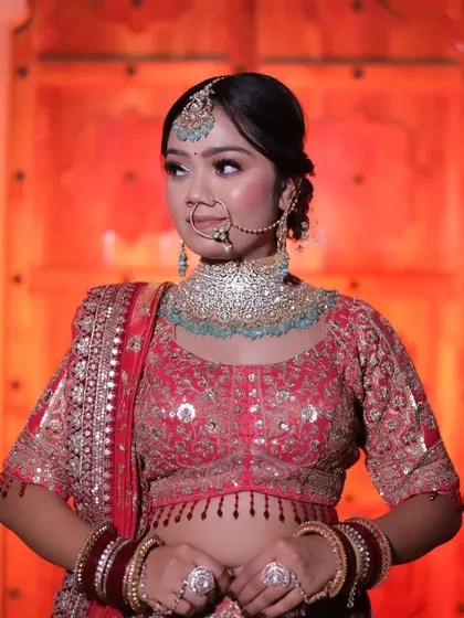 A confident pose from the bride, showcasing her complete look with the ornate red lehenga and diamond-like jewelry.