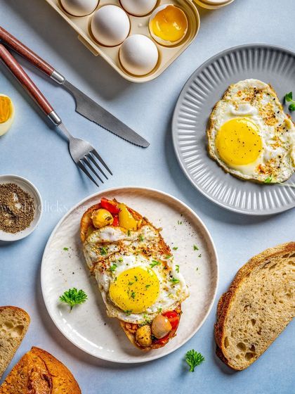 A breakfast flatlay featuring a fried egg on toast, with raw eggs and bread slices creating a complete scene.