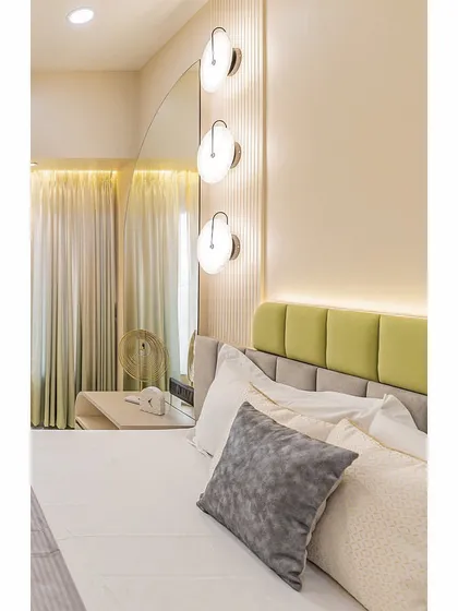 A close-up of the bedside area, featuring modern pendant lights and a custom-designed headboard that combines soft grey and pastel green upholstery.
