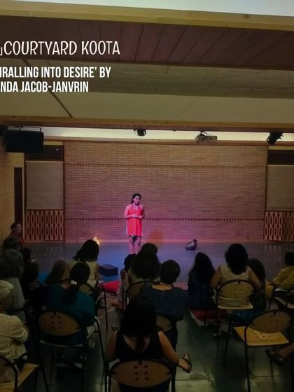 A powerful still from 'Spiralling Into Desire'. The artist stands spotlit on stage, creating a moment of intense focus and introspection in this multi-disciplinary performance.