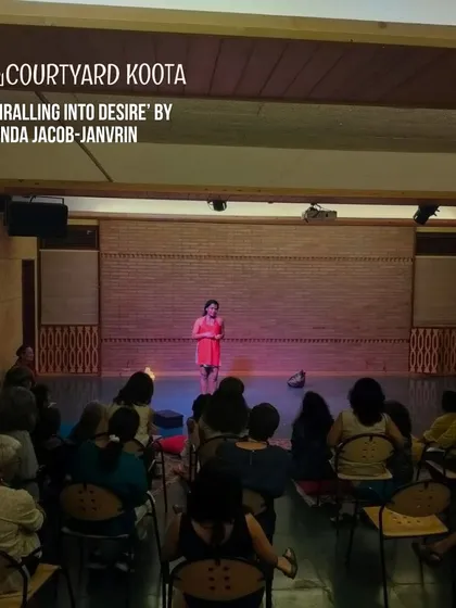 A powerful still from 'Spiralling Into Desire'. The artist stands spotlit on stage, creating a moment of intense focus and introspection in this multi-disciplinary performance.