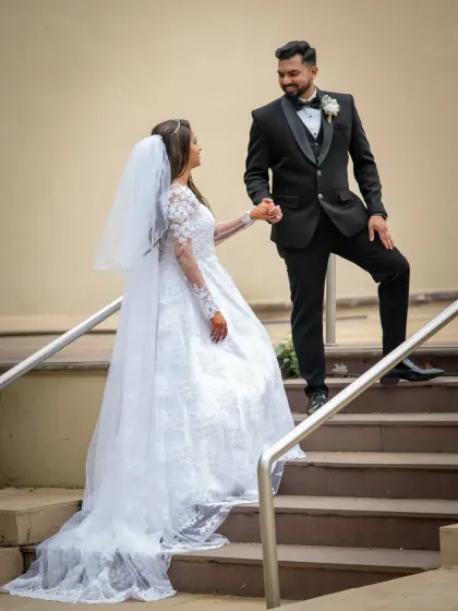 A classic pose on the stairs, with the groom leading his bride. The long train of her dress looks beautiful cascading down the steps.