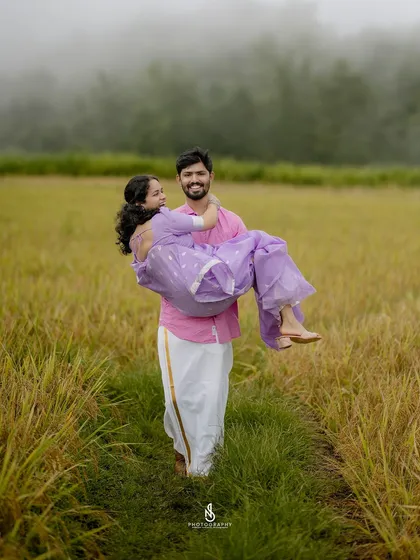 A playful and romantic moment captured in the middle of a lush green field. My goal is to document your love story through genuine interactions, like this joyful lift that shows pure happiness.