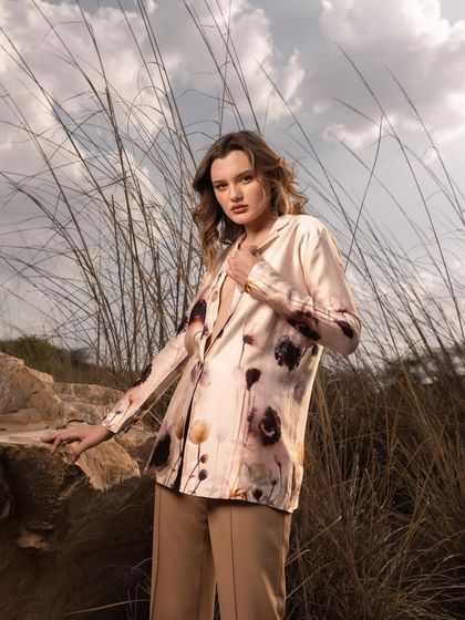 A medium shot that brings focus to the texture and print of the blazer. The natural, windswept hair and direct gaze create a confident and approachable look.