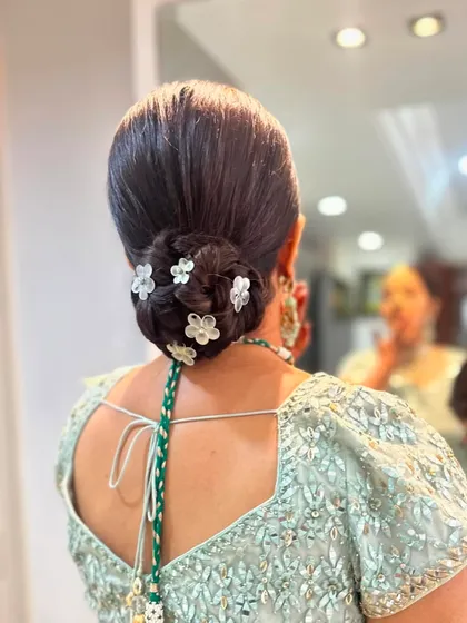 Another angle of the classic low bun with floral pins, showing the neatness and structure of the hairstyle. It's a reliable and beautiful choice for any formal occasion.