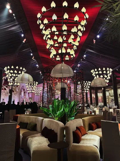 The interior of one of the London-themed event spaces, designed to feel like an upscale restaurant. The decor features modern chandeliers with a candle-like glow and plush, comfortable seating arrangements.