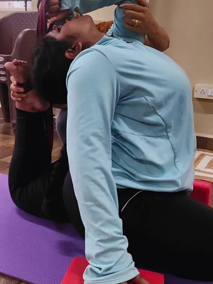 Here, I am providing hands-on assistance to a student in Poorna Rajakapotasana. Personal attention is key to helping students safely explore their limits and deepen their practice.
