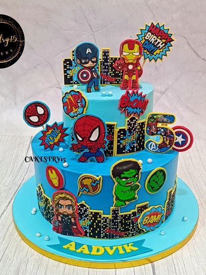 A heroic two-tier Avengers-themed cake for a 5th birthday. The blue cake is decorated with chibi-style edible images of Thor, Iron Man, Captain America, and other heroes.