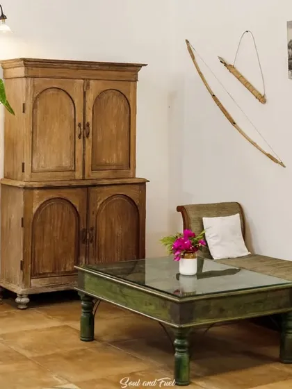 A cozy corner in Z Farms, with rustic wooden furniture and a traditional bow and arrow as wall decor. The space has a warm, earthy, and lived-in feel.