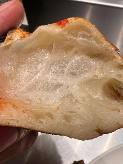It's all about the crust. We're obsessed with getting that light, airy, and perfectly chewy Neapolitan texture. This is a look inside our dough after it's been fire-kissed in the oven.