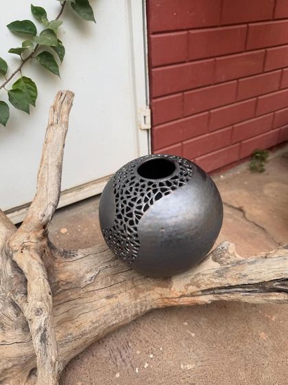 This wheel-thrown stoneware sphere features an intricate, hand-carved geometric pattern. I added a touch of gold to the metallic glaze to highlight the cuts and create a sense of depth.
