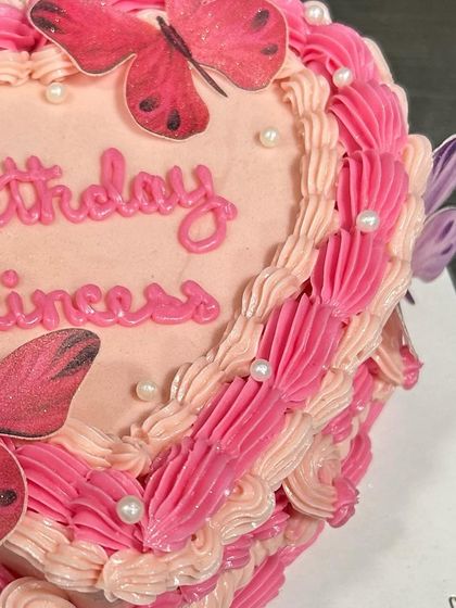 The detailed piping work on the side of the pink heart-shaped butterfly cake.