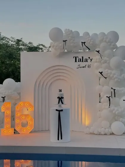 The sweet 16 setup with the marquee number '16' lit up as dusk approaches, adding a warm glow to the poolside celebration.