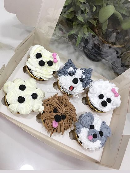 Another angle of the puppy cupcakes, showing the variety of breeds and details like little pink bows and tongues. These custom cupcakes are always a hit at parties.