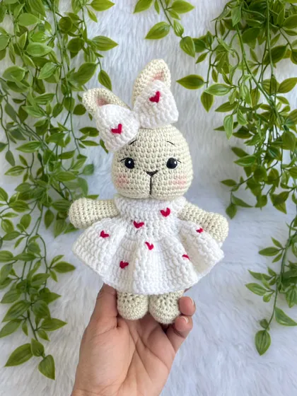 This sweet bunny is dressed in a white frock adorned with little red hearts. The matching bow on her ear makes her extra cute. A perfect gift for Valentine's Day or for someone you love.