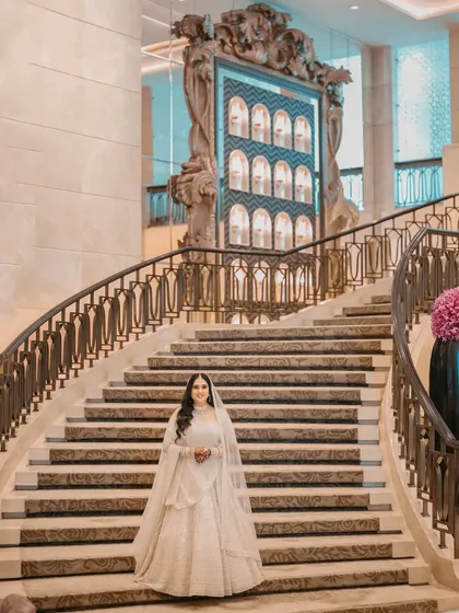 A vision in white. The bride poses on the magnificent staircase of the St. Regis, looking every bit like a queen.