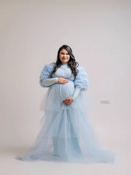 Feel like a queen in one of our ethereal tulle gowns. This portrait highlights the elegance and grace of pregnancy, using soft studio lighting to create a bright and airy feel.