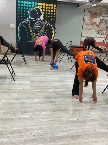 A group of students in a supported forward fold, working on their flexibility together.