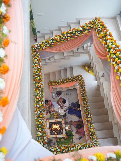 An overhead view of the housewarming ceremony in progress. The floral mandap built over the staircase creates a stunning and unique setting for the traditional pooja.