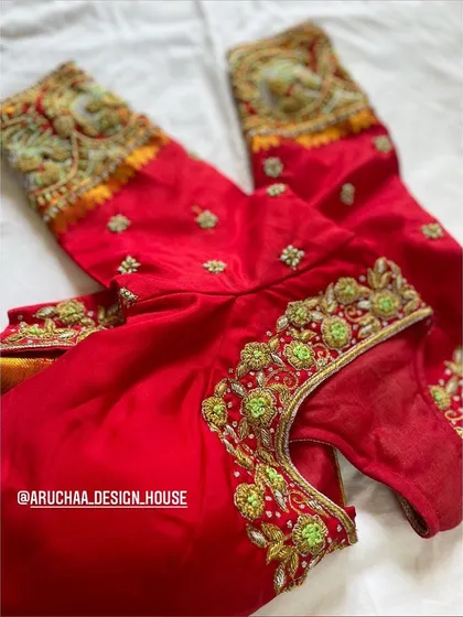 Another view of the embellished red blouse, showcasing the detailed embroidery work along the neckline and sleeves.
