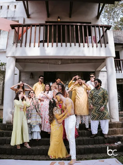 A playful and slightly cheeky moment as the couple kisses during their Haldi, while their friends and family cover their eyes in the background.