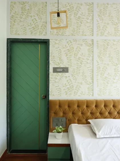 The bold green door with a diagonal pattern and a single brass inlay adds a pop of color and a unique design detail to this earthy bedroom.