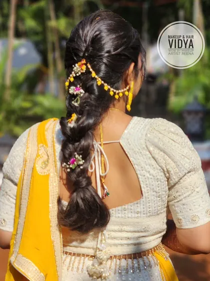 A detailed shot of the braided hairstyle Vidya created for Priya's haldi. The floral accessories add a perfect festive touch.