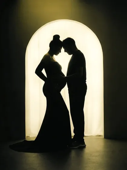 There is a special magic in silhouette portraits. This image focuses purely on the connection between the expecting parents, their shapes telling a story of love and anticipation against a warm, glowing archway in my studio.