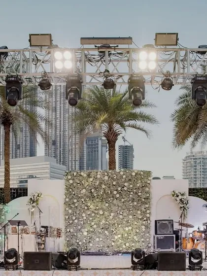 The stage for the 'White Wonderland' event, with the city skyline of Dubai creating a stunning modern backdrop. The stage itself was adorned with a wall of fresh white flowers.