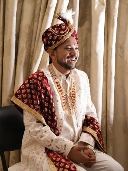 A candid shot of the groom, smiling happily as he waits during the wedding preparations.