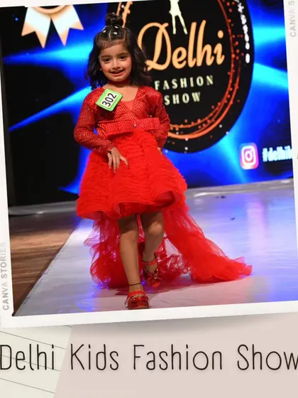 Dressed in a vibrant red gown with a long tulle train, this little model is the center of attention. The professional lighting makes the color pop on stage.